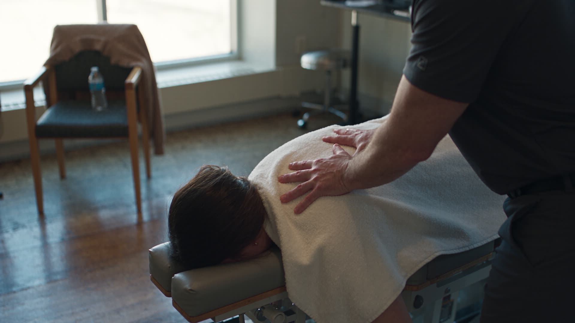 A practitioner at work over a treatment table in a bright wellness clinic